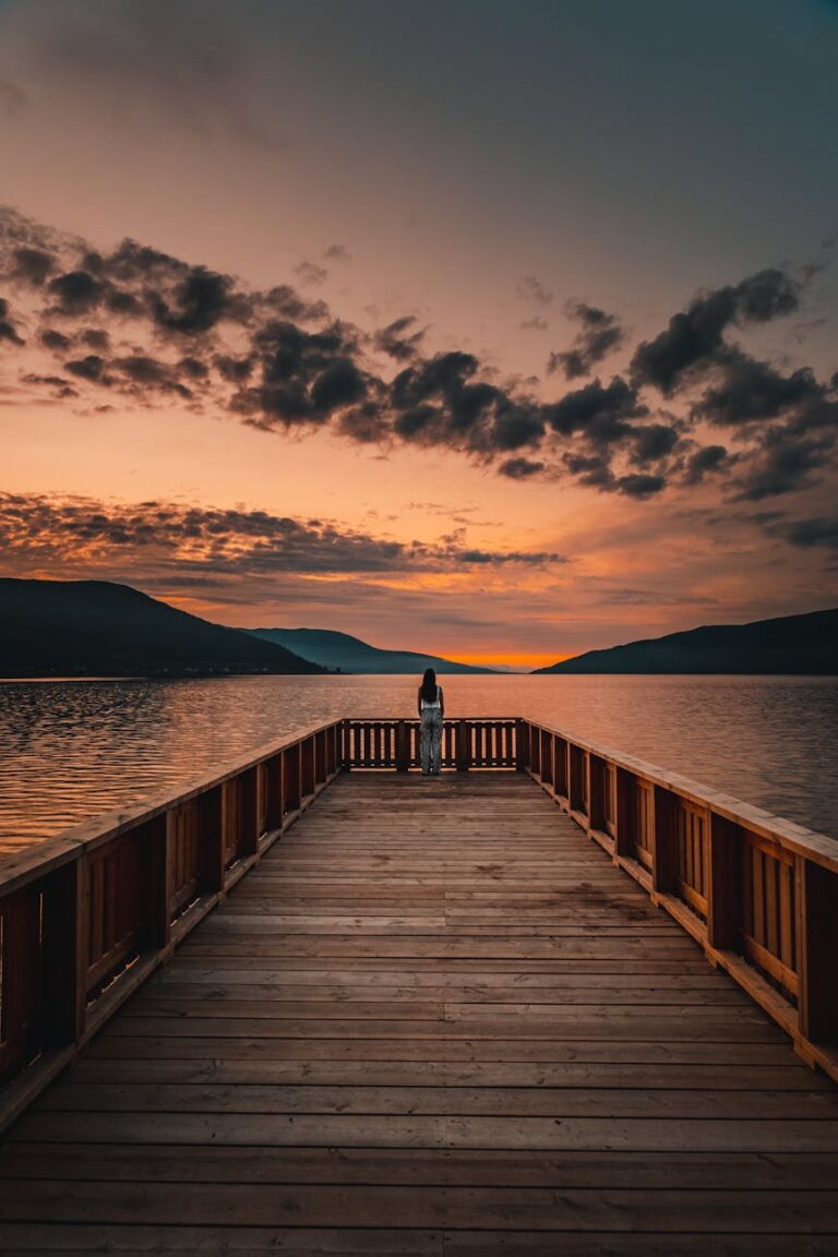 wooden pier against mountains and sunset sky